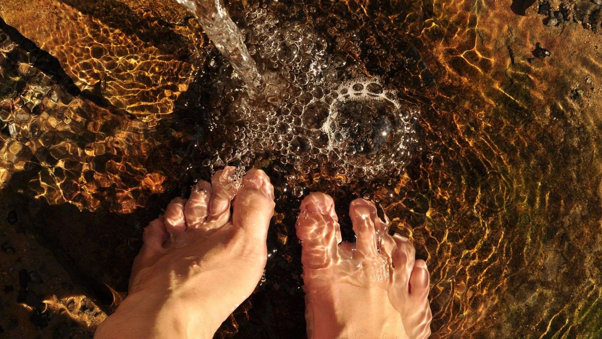 Escapadas cerca de Madrid Pies mojándose en el agua del río en una escapada a la sierra de Madrid